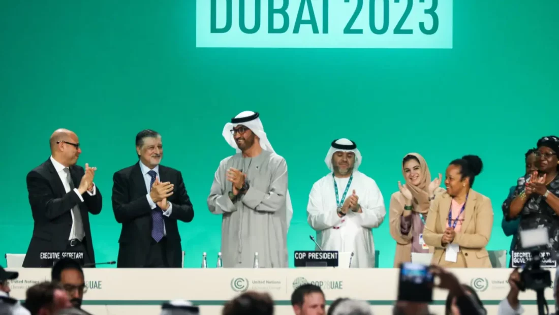 people are clapping in front of a giant screen written Dubai 2023 on it